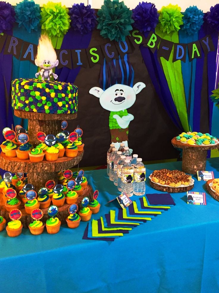 a table topped with cakes and cupcakes on top of a blue table cloth