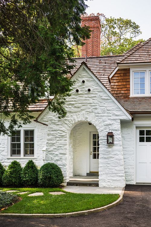 a white brick house with green grass and trees