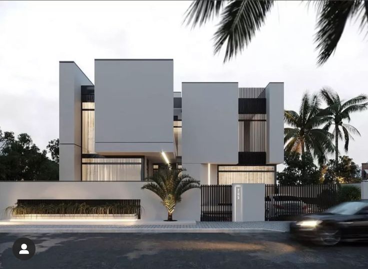 a car driving past a tall white building with palm trees on the side of it