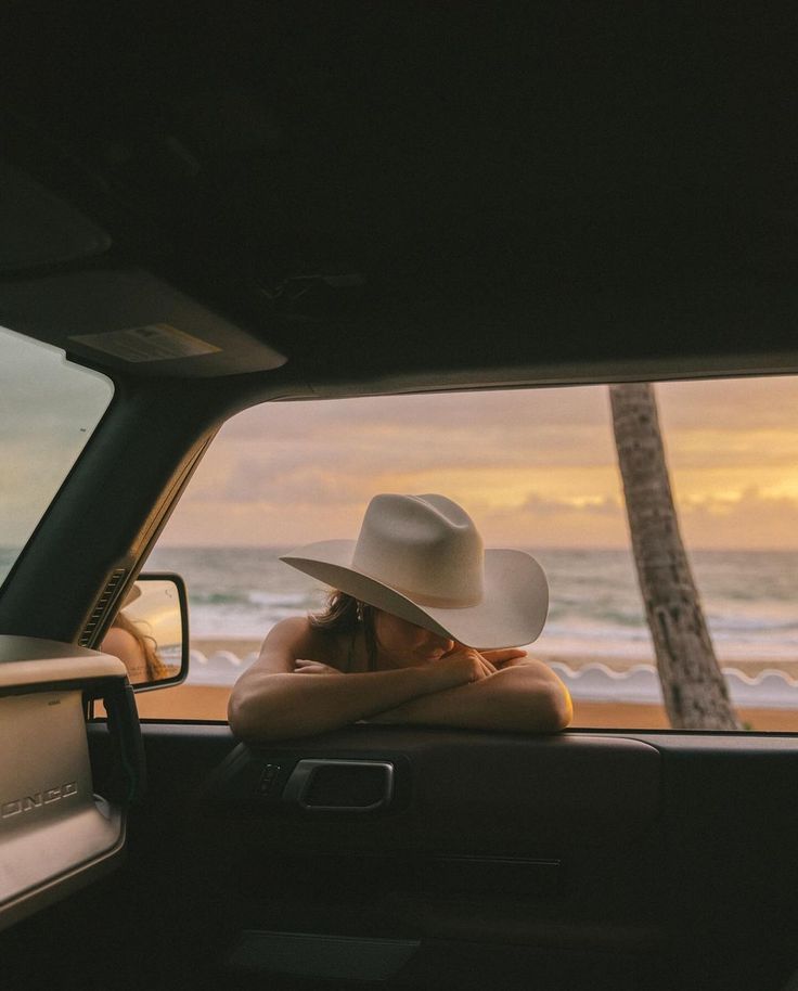 a woman wearing a white hat sitting in the back of a truck with her arms crossed