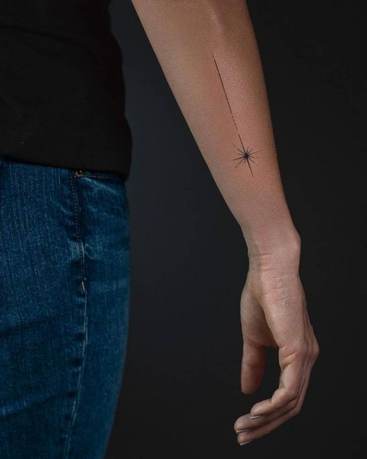 a woman's arm with a small star tattoo on it