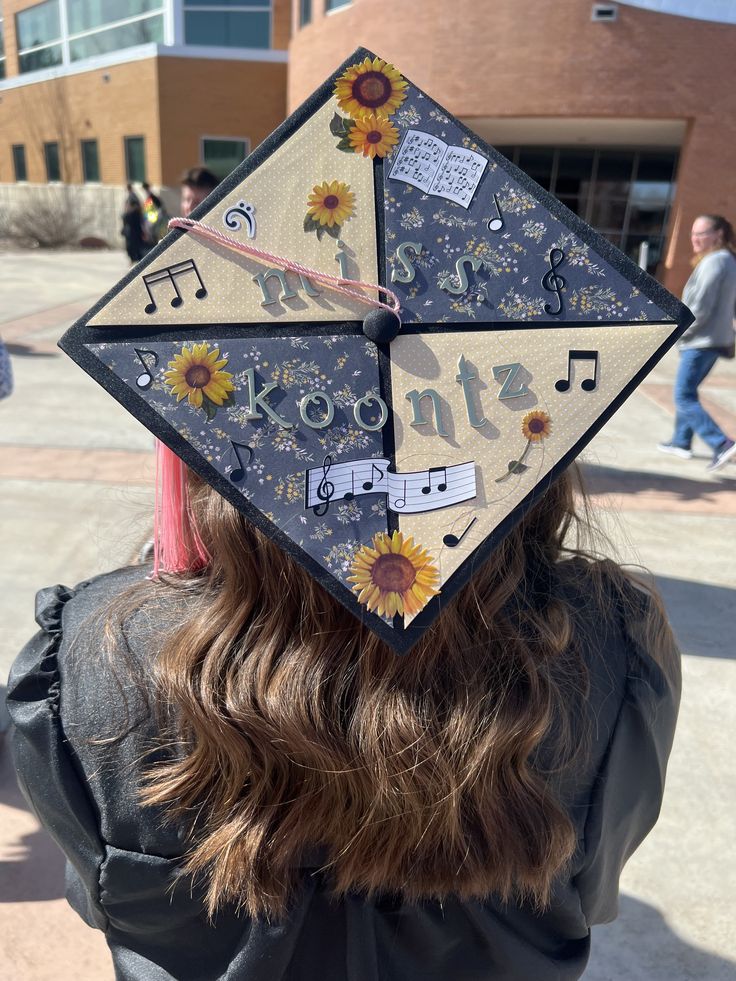 An SUU graduate facing away from the camera, so the top of their grad cap is visible. Their grad cap is decorated with four quadrants of different background paper. There are music note and sunflower stickers, as well as stickers spelling out "Miss Koontz." Piano Graduation Cap, Marching Band Graduation Cap, Grad Cap Music Ideas, Communications Graduation Cap, Music Education Graduation Cap, Music Major Graduation Cap, Music Teacher Graduation Cap, Grad Cap Ideas Teacher, Art Major Graduation Cap