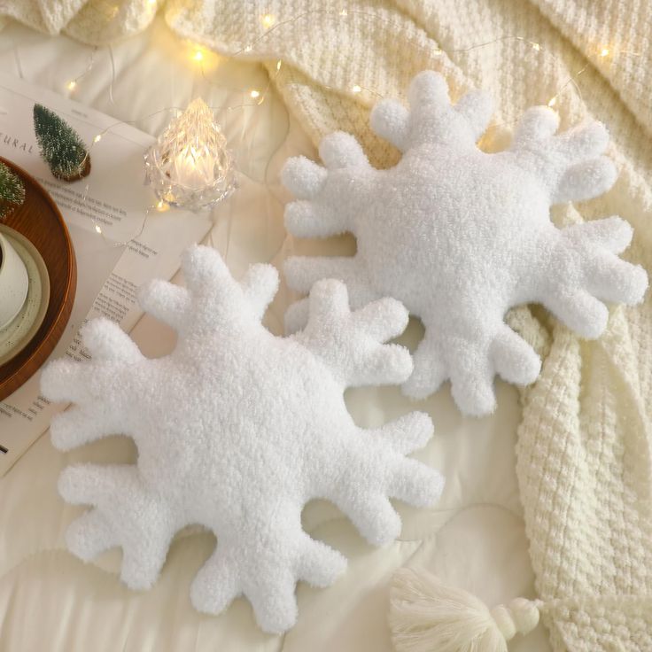 two white snowflakes sitting on top of a bed next to christmas decorations