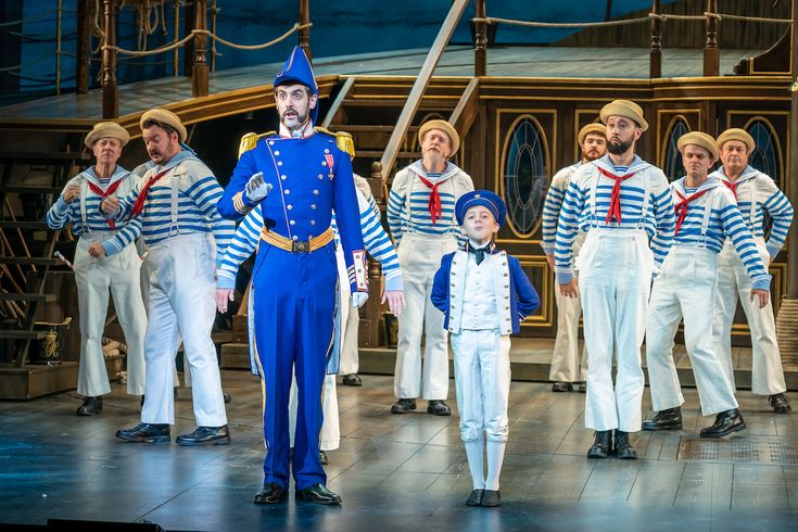 a group of people standing on top of a stage next to each other wearing blue and white outfits