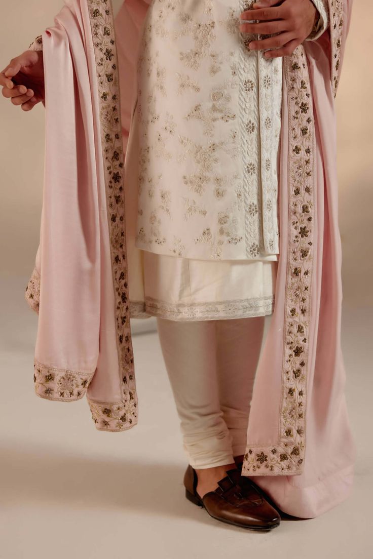 Editor's Note Featuring our work of art in our white all-over hand-embroidered sherwani set. The foundation is crafted using tone-on-tone thread along with silver zari work as a base texture. Paired with a baby pink hand-embroidered stole safa. Fabric: Linen silk Color: White Components: Sherwani, kurta, churidar, stole, safa and cummerbund Occasion: Groom Fit: Regular Note: Product colour may slightly vary due to photographic lighting sources Care: Dry clean only About the Designer After establ Pink Sherwani, Embroidered Sherwani, Blouse Yoke, Personal Shopping Service, Zari Work, The Foundation, Churidar, Custom Tailoring, Monk Strap