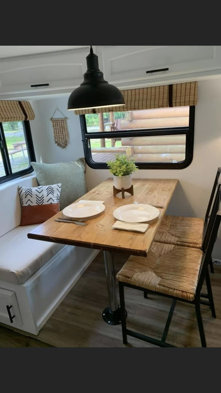 a kitchen table with two plates on it next to a couch and window in the background