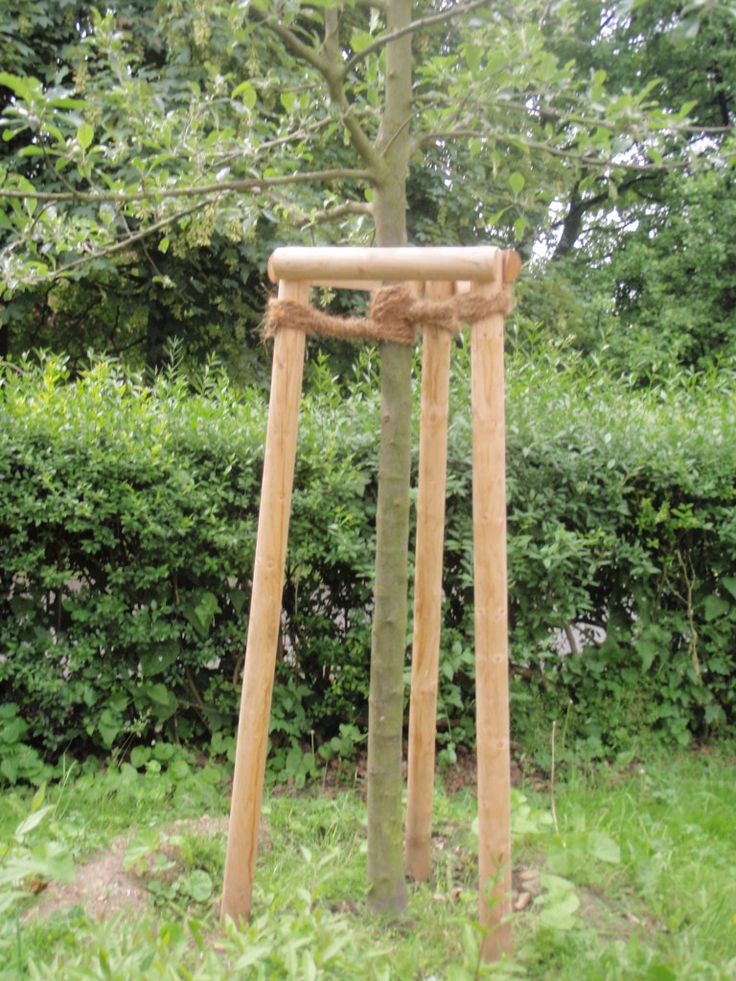 a wooden swing in the grass near a tree