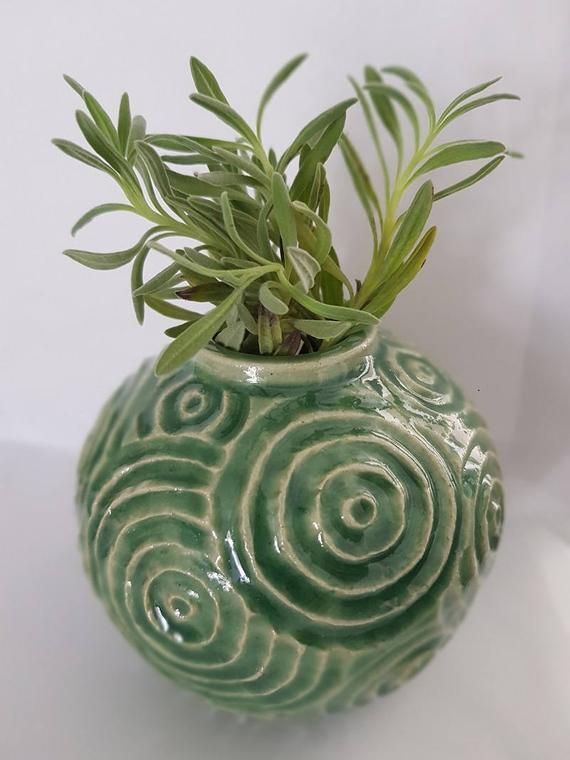 a green vase with some plants in it