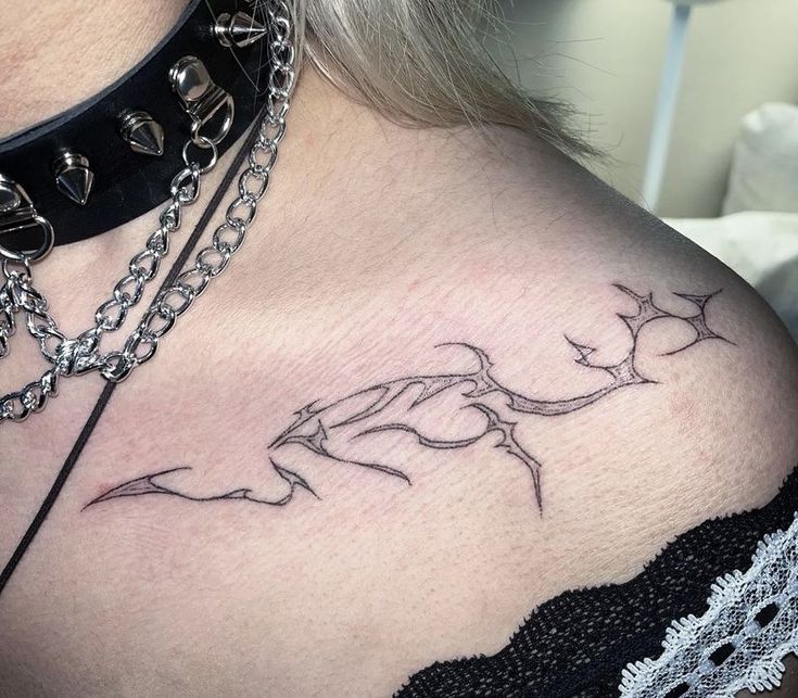 a woman's chest with a tattoo on it and a chain around her neck