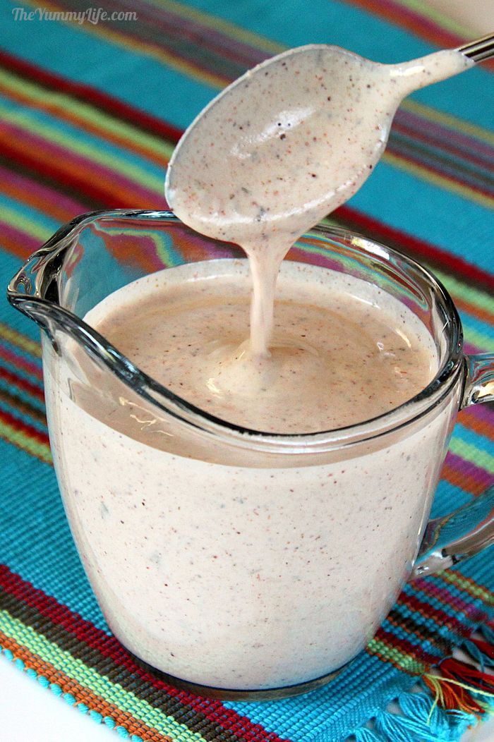 a spoon is being used to dip into a white liquid in a glass mug on a colorful place mat