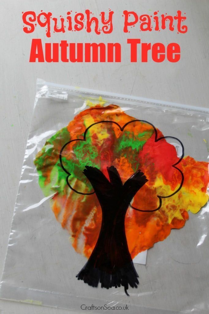 a tree made out of colored paper on top of a plastic bag with black hands