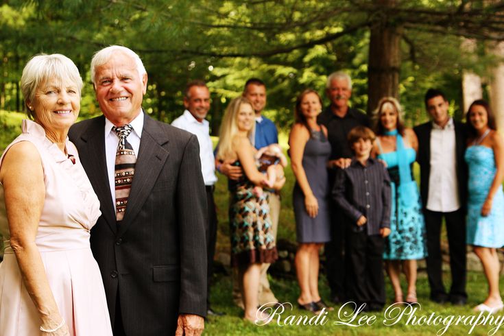 a group of people standing in front of trees and grass with one man wearing a suit and tie