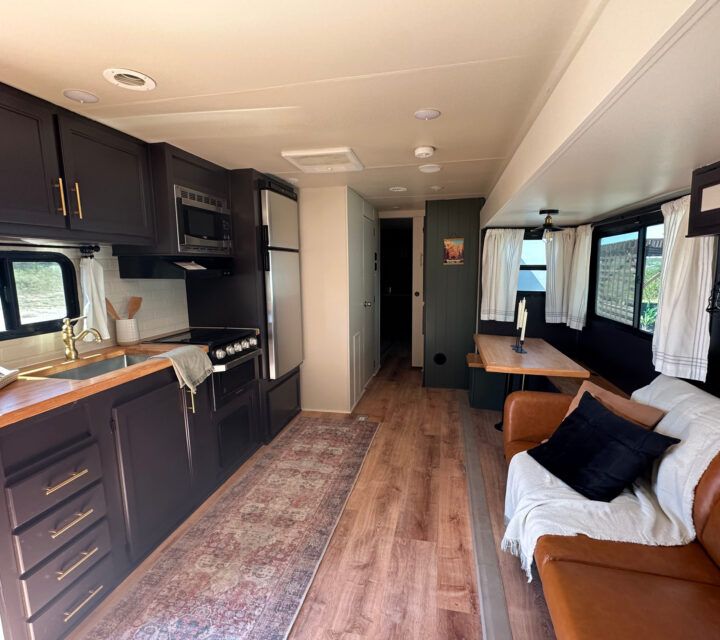 the interior of an rv with wood flooring and black cabinets, including a couch