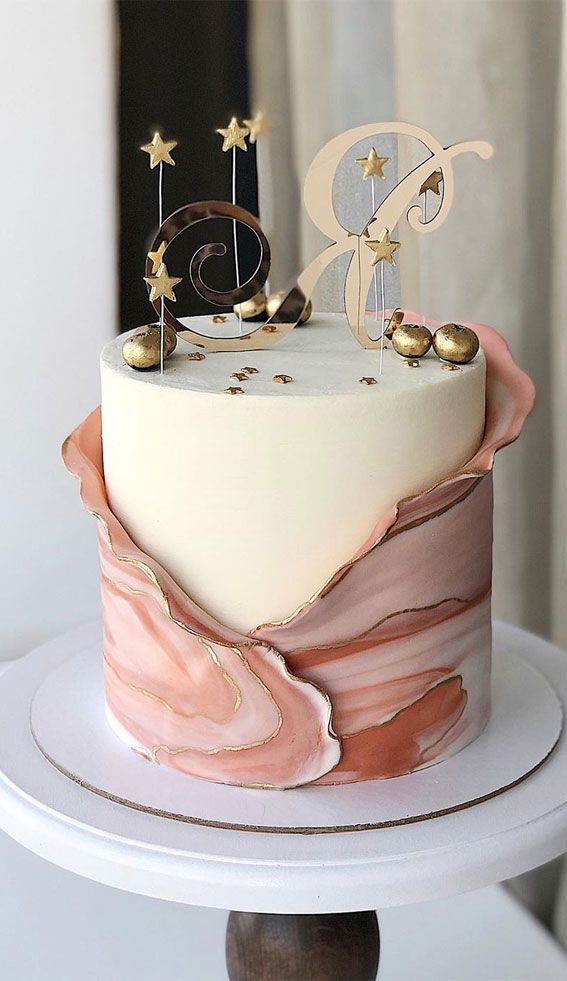 a white cake with pink and gold frosting