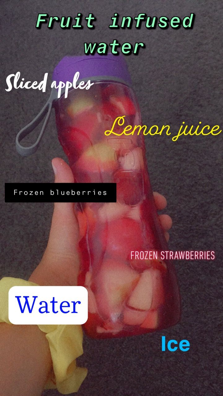 a hand holding a frozen water bottle filled with sliced apples and lemon slices in it