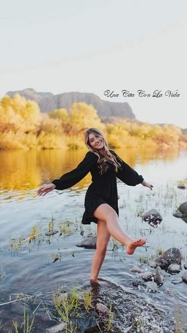 a woman standing in the water with her arms out and legs spread wide, smiling at the camera