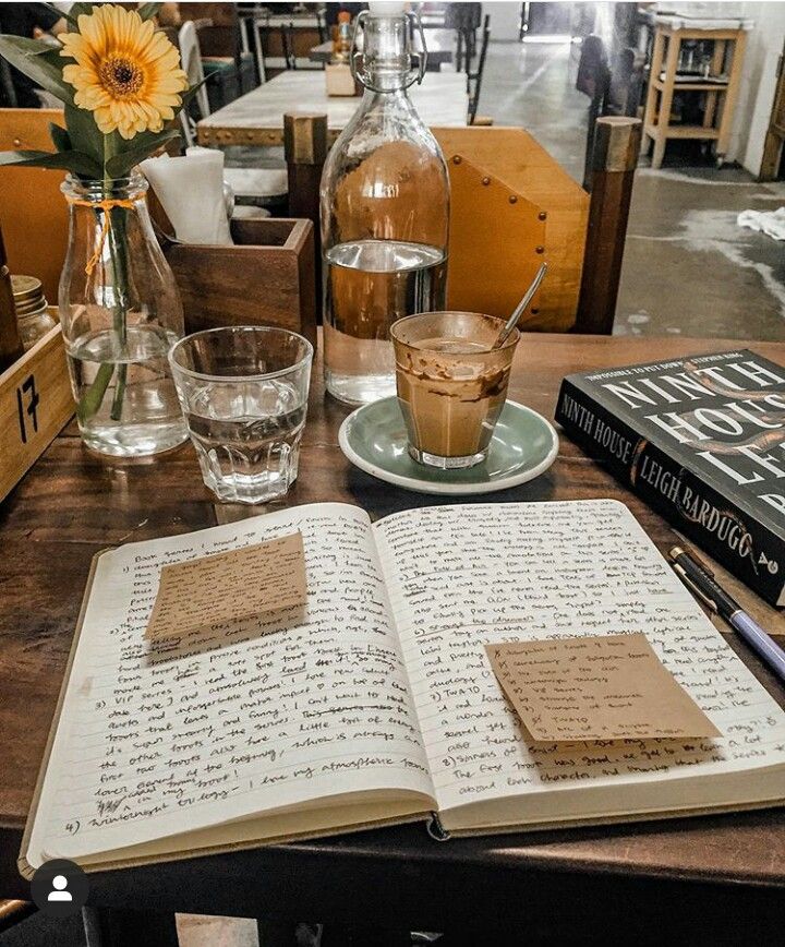 an open book sitting on top of a wooden table next to two glasses and bottles