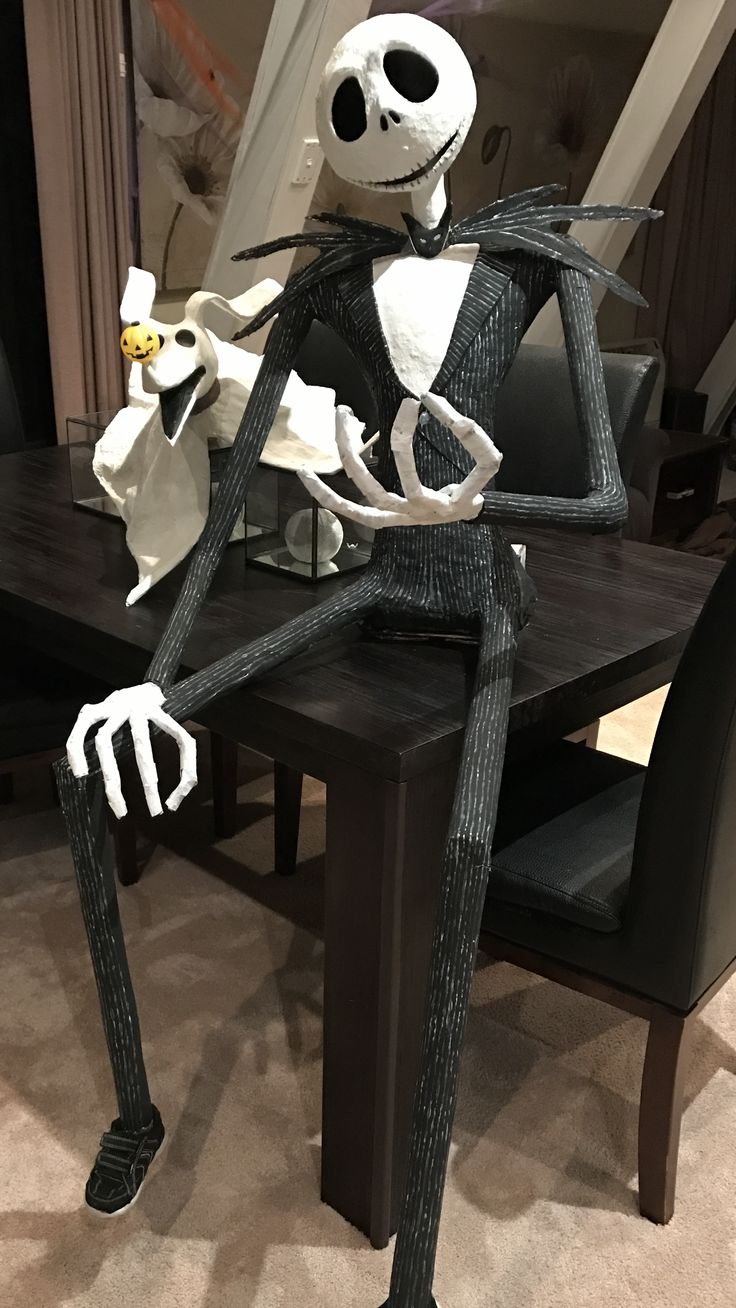 a skeleton sitting on top of a wooden table next to a black dining room table