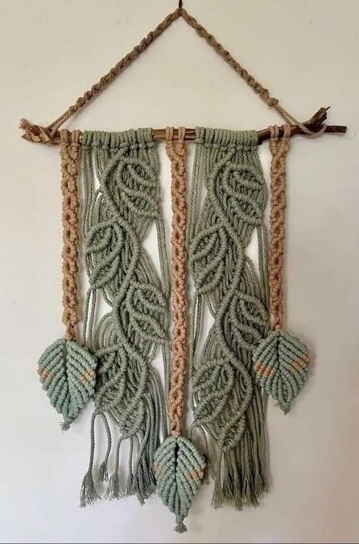 a wall hanging made out of macrame and rope with leaves attached to it