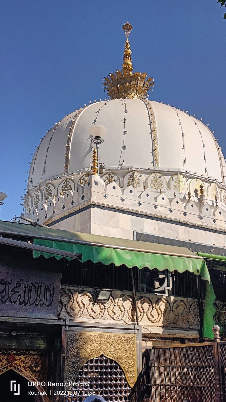 an ornate white building with green awnings and gold decorations on it's roof