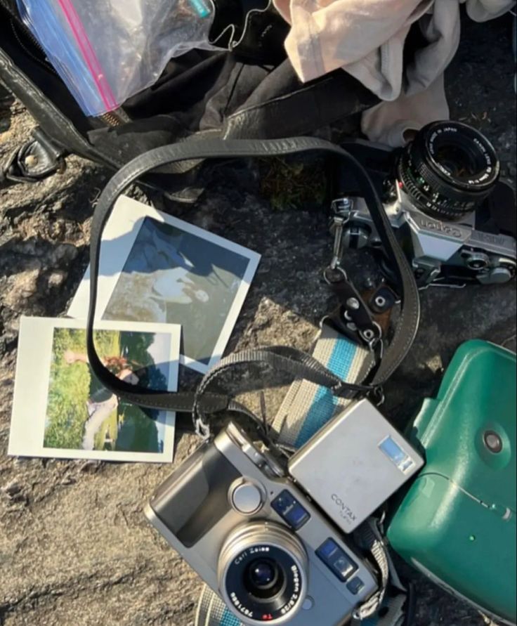 an old camera sitting on the ground next to some other items and a book bag