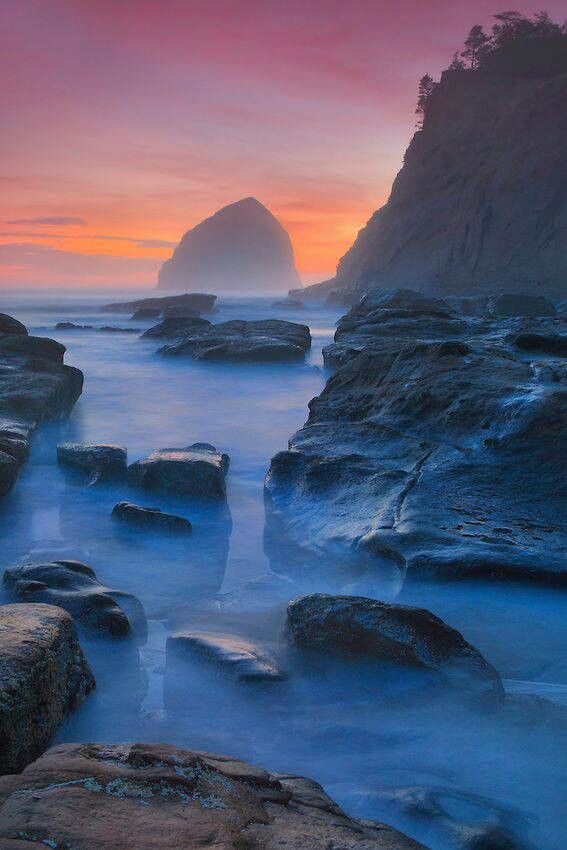 the sun is setting over some rocks in the water and it looks like they are going to fall