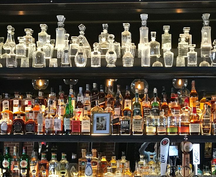 many bottles and glasses are lined up on the shelf