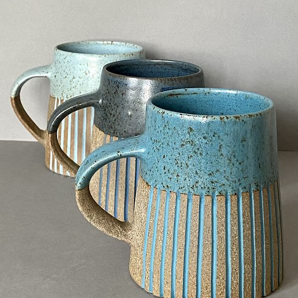 three coffee mugs sitting next to each other on top of a gray countertop