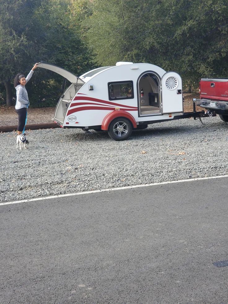 a man standing next to a red and white camper trailer with its door open