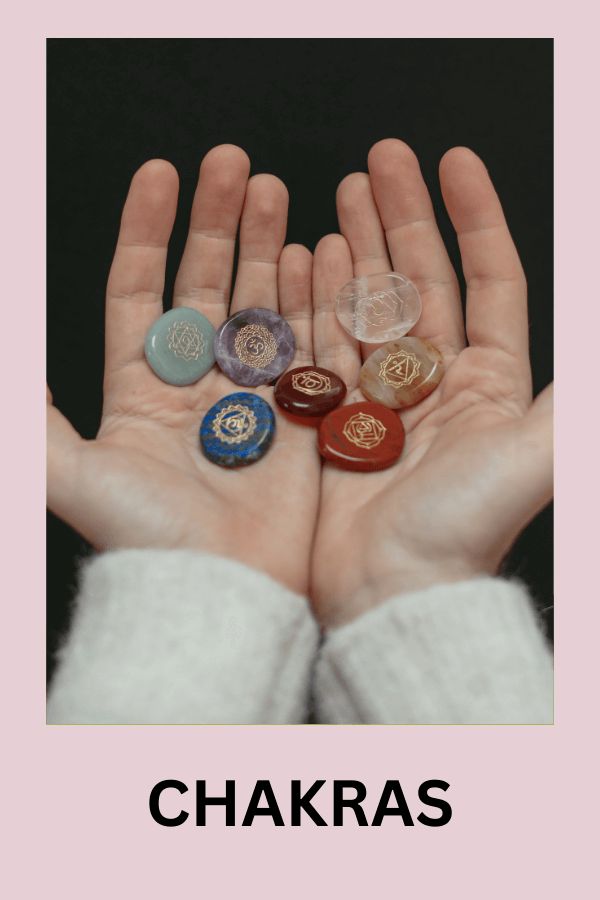 a person's hands with five different colored buttons in their palms and the words chakras above them