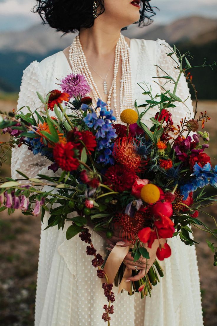 a woman holding a bouquet of flowers in her hands and looking off into the distance