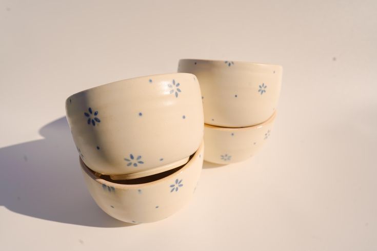 two white cups with blue flowers on them are sitting side by side in front of each other