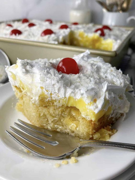 a piece of pineapple poke cake on a plate with a fork next to it