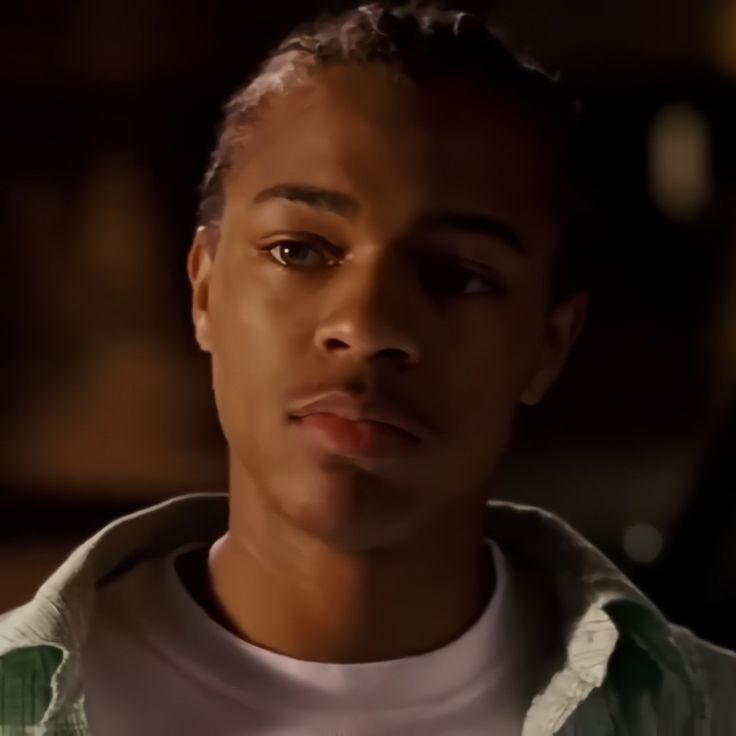 a close up of a person wearing a white shirt and looking at the camera with an intense look on his face