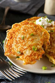 three pancakes on a plate with sour cream and scallions in the background, next to a bottle of ginger syrup