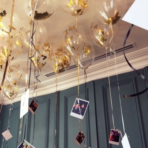 some balloons hanging from the ceiling with photos attached to them and streamers in front of them