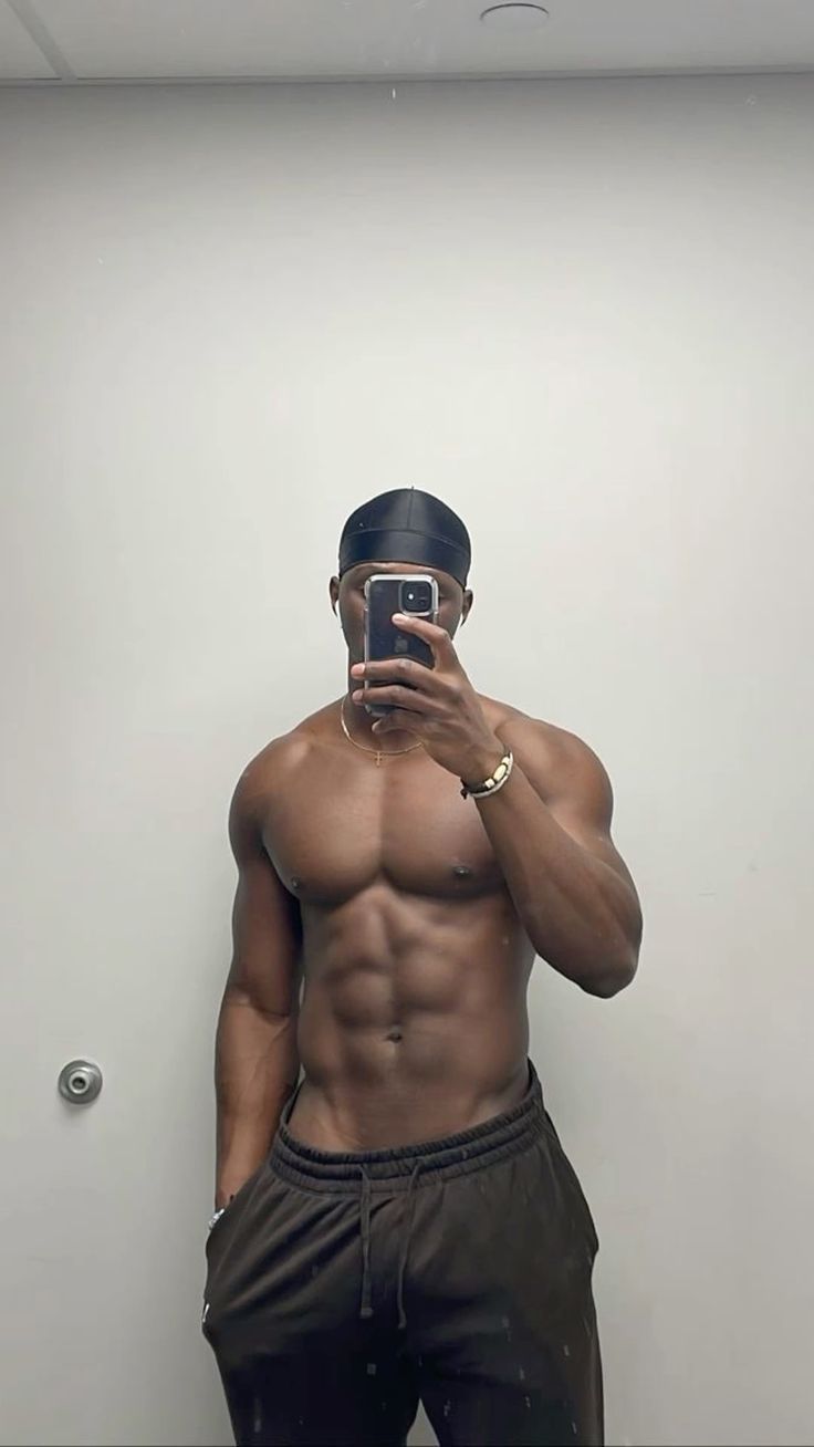 a shirtless man taking a selfie in front of a mirror with his cell phone