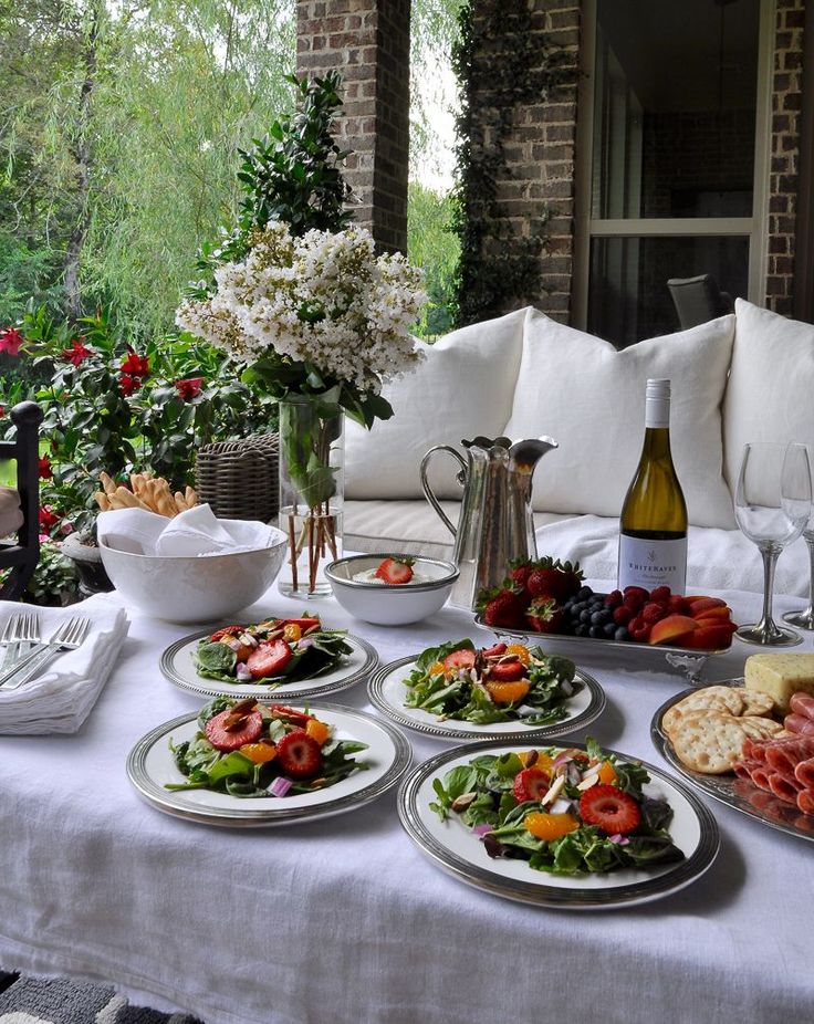 a table topped with plates of food next to a vase filled with flowers and wine