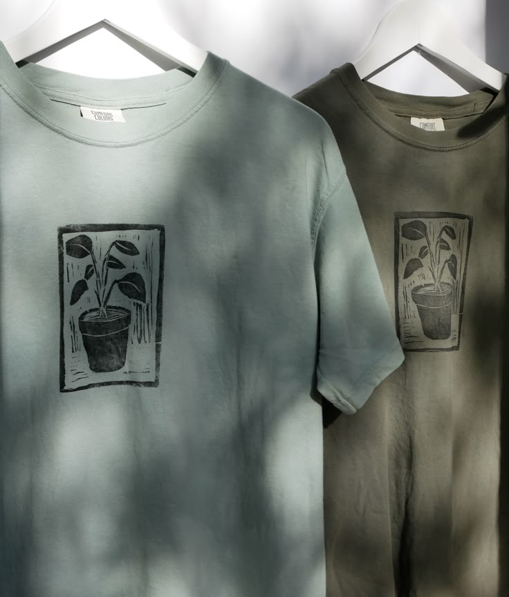 two t - shirts with plants on them hanging up