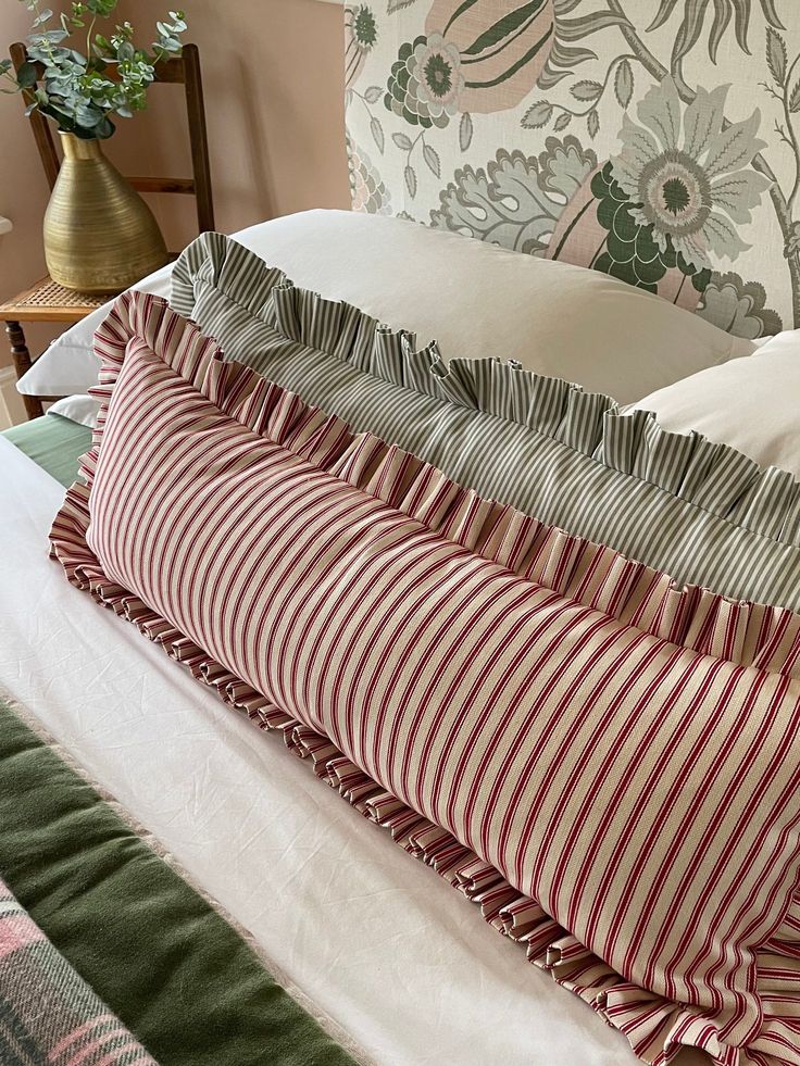 four pillows stacked on top of each other in front of a floral wallpapered headboard