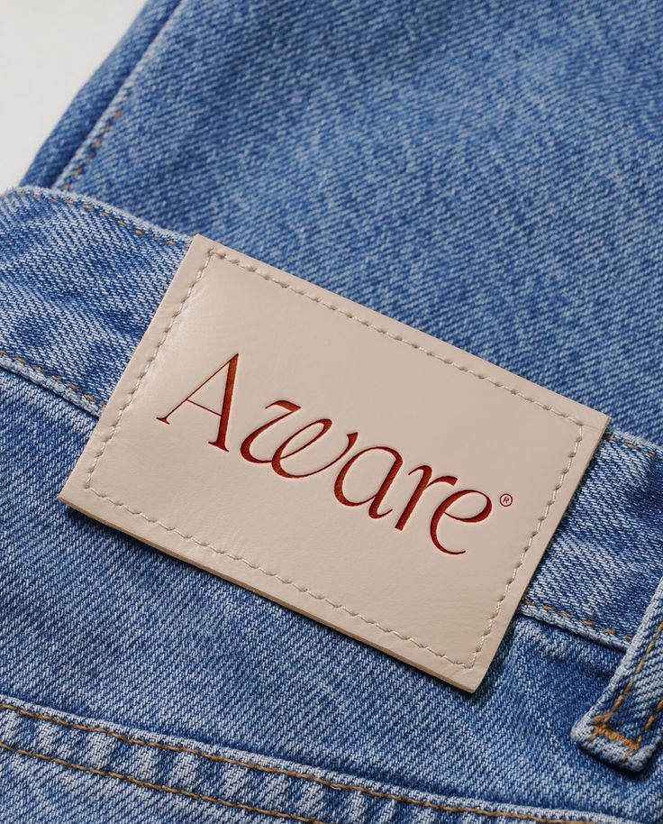 a name tag on the back of a pair of blue jean pants with red lettering