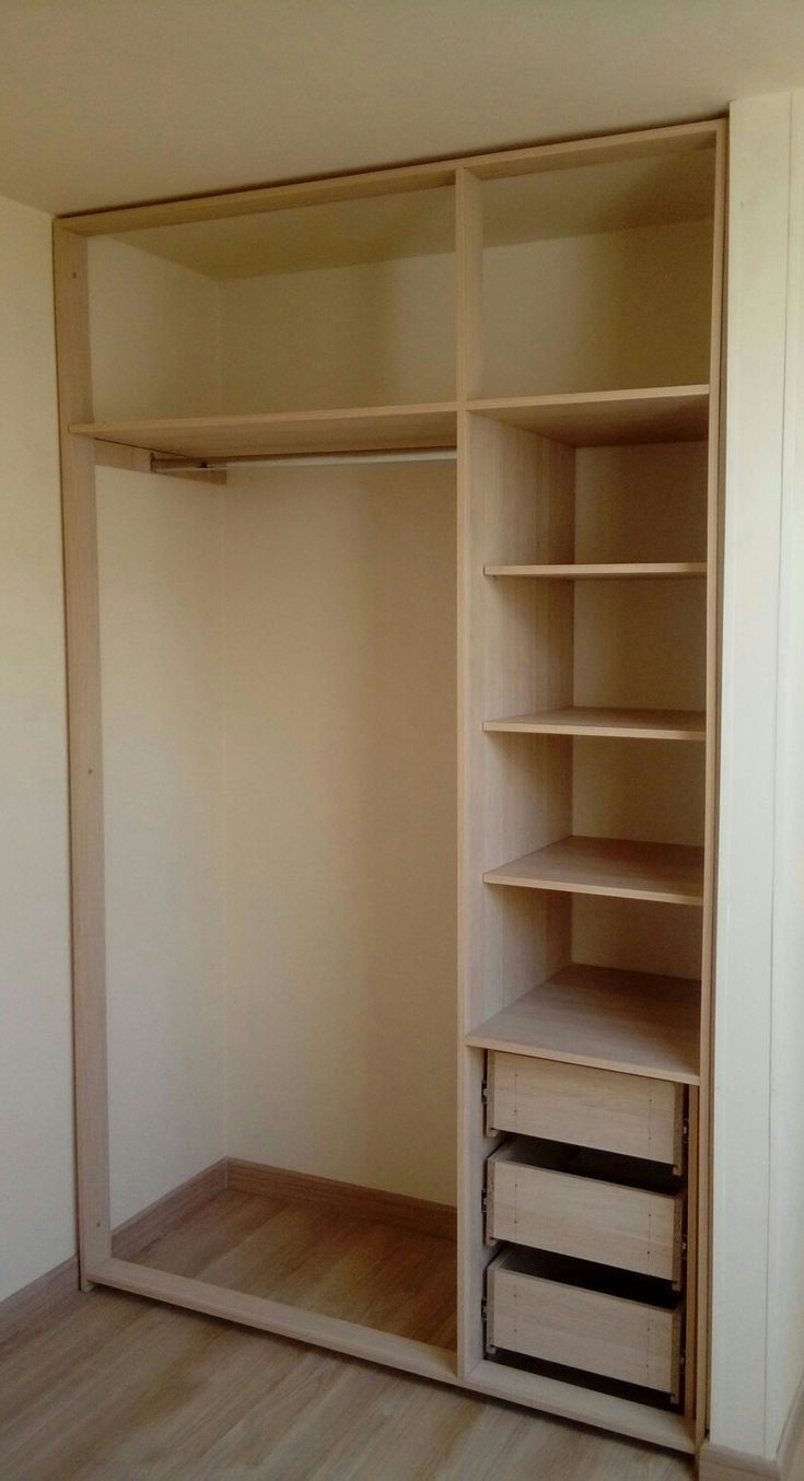 an empty closet with shelves and drawers in the corner, next to a white wall