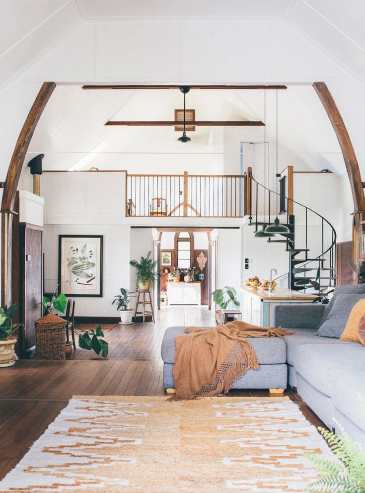 a living room filled with furniture and a spiral staircase leading up to the second floor