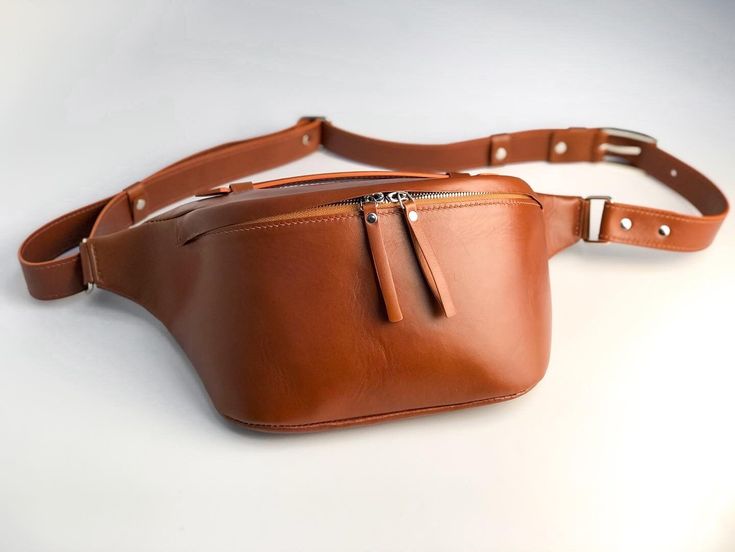 The leather bum bag made of natural material will be a convenient and reliable assistant on walks and in everyday life. The custom fanny pack bag for women has a main compartment and an outer zippered pocket on the back of the bag. The belt bags also have an adjustable main strap and handle to carry the bag in your hand.    The  leather hip bag is made of brown leather on the outside and beige leather on the inside. The favorite for its versatility and stylish look belt bag make a beautiful pers Brown Sling Bag, Leather Bum Bag, Fanny Pack Women, Leather Hip Bag, Personalized Leather Wallet, Pack Bag, Bridesmaid Bags, Leather Fanny Pack, Leather Belt Bag