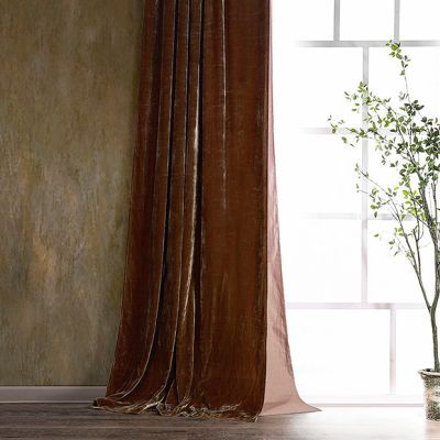 a vase with a plant in it sitting next to a brown curtain on a window sill