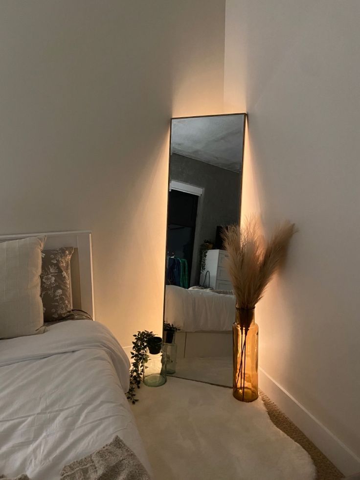 a bedroom with a bed, mirror and plants on the floor in front of it