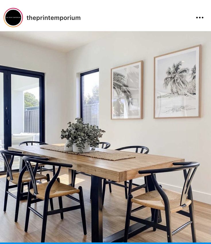 a dining room table with chairs and pictures on the wall in front of it,