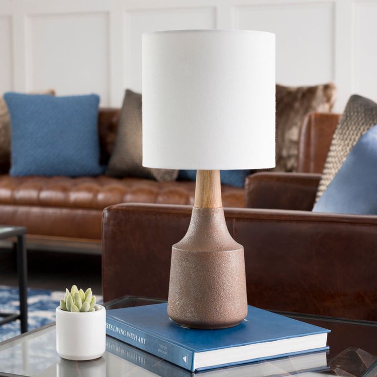 a table lamp sitting on top of a glass table next to a couch and chair