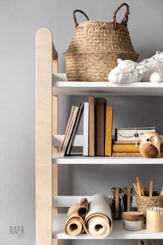 a book shelf with books, baskets and other items on it in a room that has gray walls