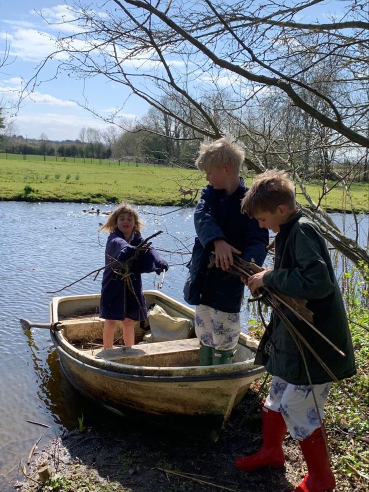 three children are standing in a boat on the water